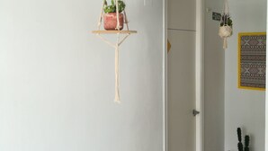 Un couloir orné d’un support à plantes en macramé et d’une décoration murale en macramé.