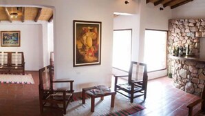 Una habitación amplia con chimenea de piedra, muebles de madera y obras de arte en las paredes.