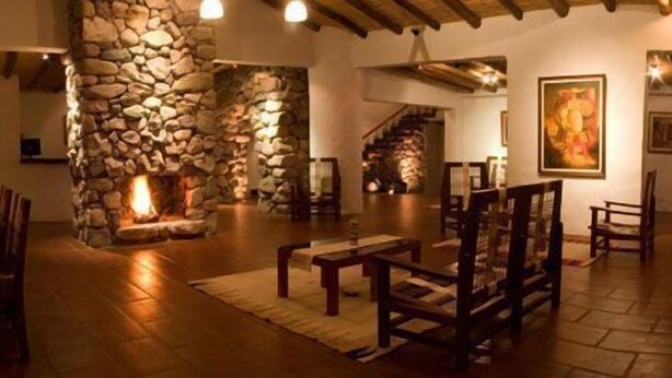 Un interior acogedor con chimenea de piedra, muebles de madera y una escalera.