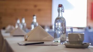 A table set with a bottle labeled "ACQUA DI NOI," a glass, a cup, and a napkin.