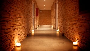 A corridor with brick walls and a tiled floor, illuminated by wall-mounted lights. - Noi Puma Lodge (Machalí)