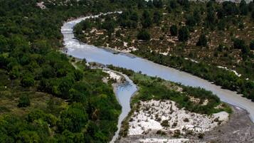Un río serpentea a través de un paisaje montañoso de exuberante vegetación y terreno rocoso.