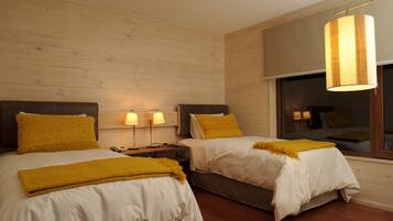 A hotel room with two beds, wooden walls, and a large window.