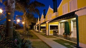 A row of yellow buildings with white trim, each with a covered outdoor seating area and a single visible window.