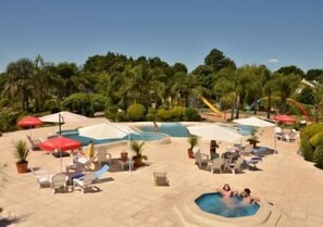 Un espace piscine comprenant plusieurs piscines, des chaises longues et des parasols.