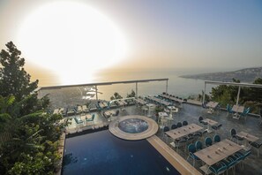 A rooftop pool area with a view of the sea, outdoor seating, and a circular water feature. - Bay Lodge (Jounieh)