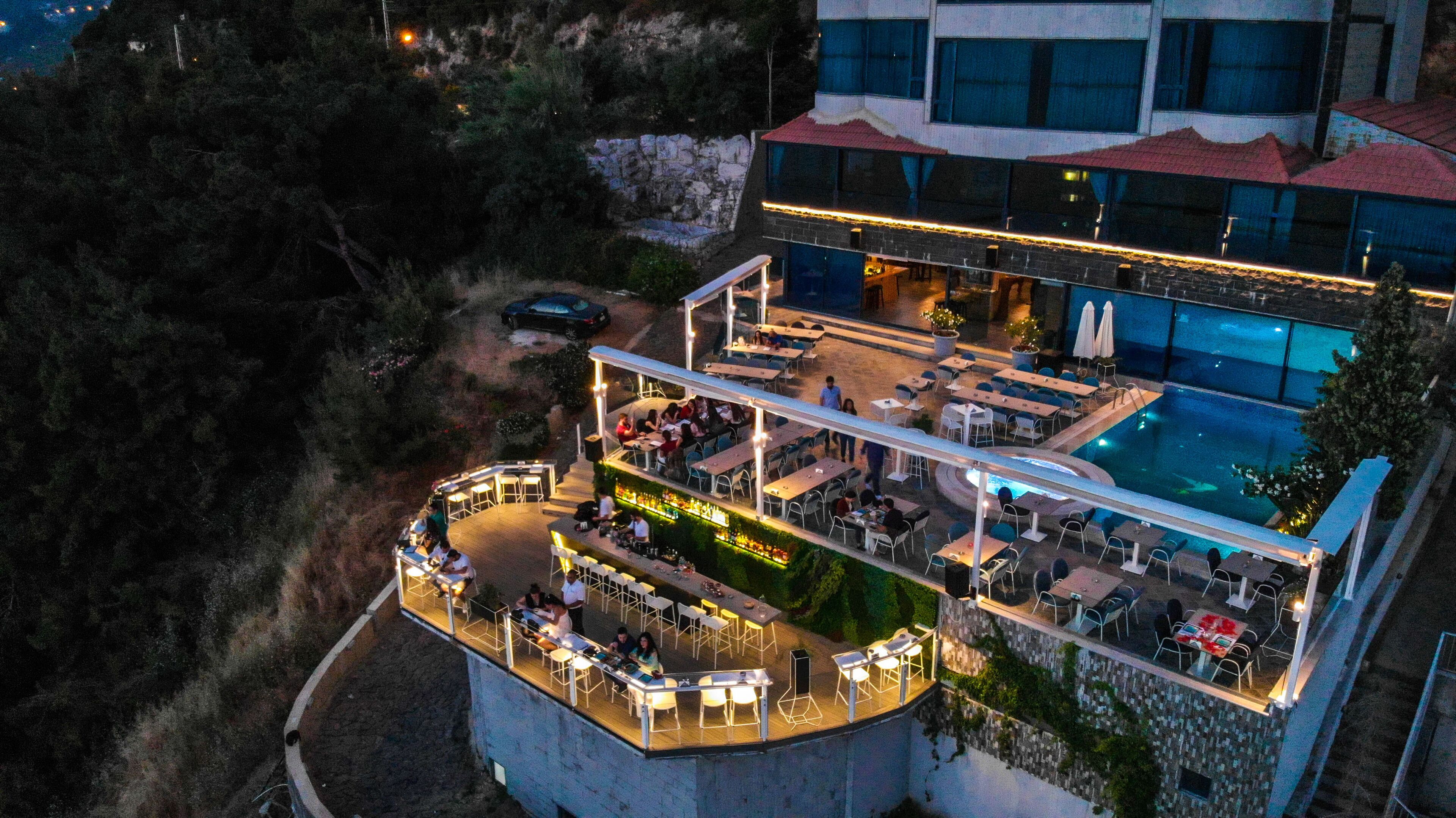 An outdoor terrace with multiple dining areas, a bar, and a pool.