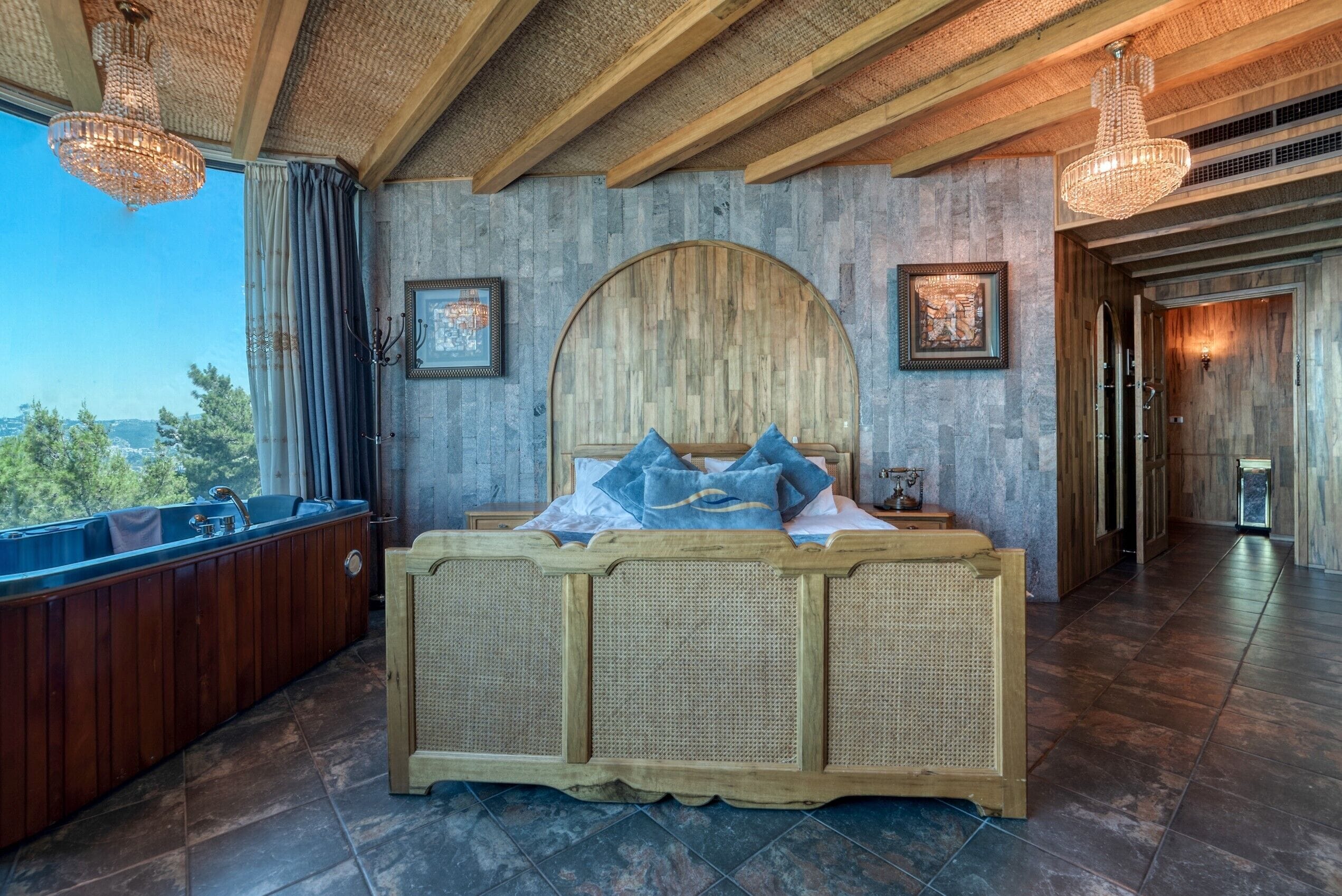 Un dormitorio con una cama grande, un cabecero de madera, una bañera y vistas al exterior.