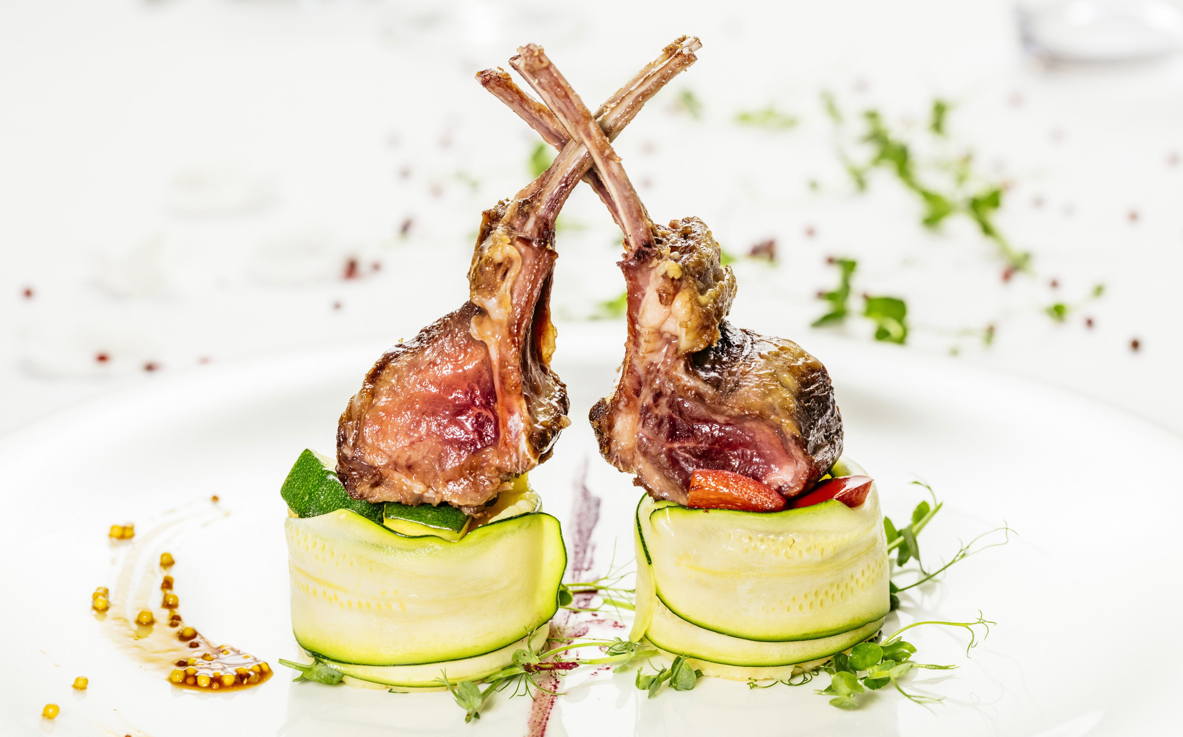 Two lamb chops on a plate with cucumber slices and garnishes.