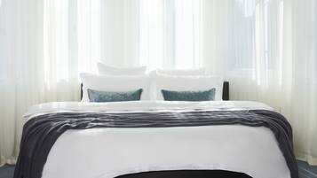 Un dormitorio moderno con una cama grande, cortinas blancas y una lámpara colgante.