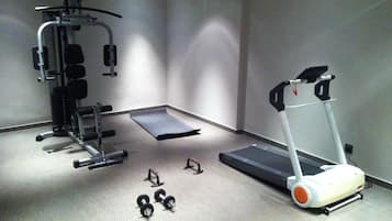 A gym with a treadmill, weight bench, and various exercise equipment.