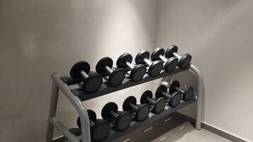 A metal rack with multiple pairs of black dumbbells.