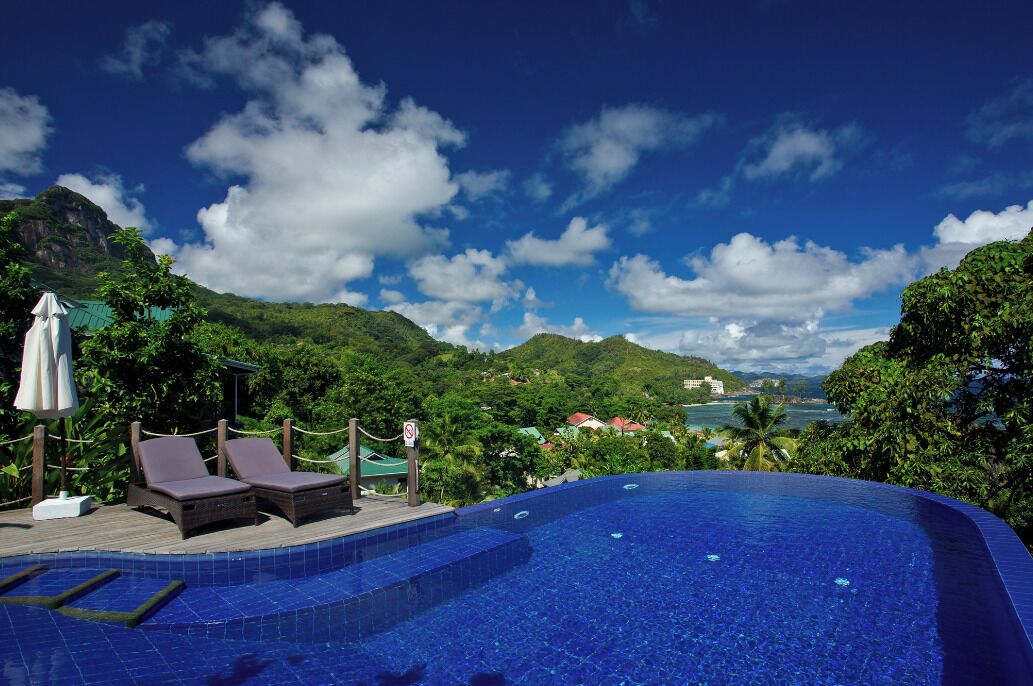 A pool area with lounge chairs and a view of a mountainous landscape.