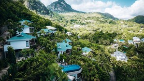 Een resort met meerdere gebouwen, een zwembad en weelderige begroeiing.