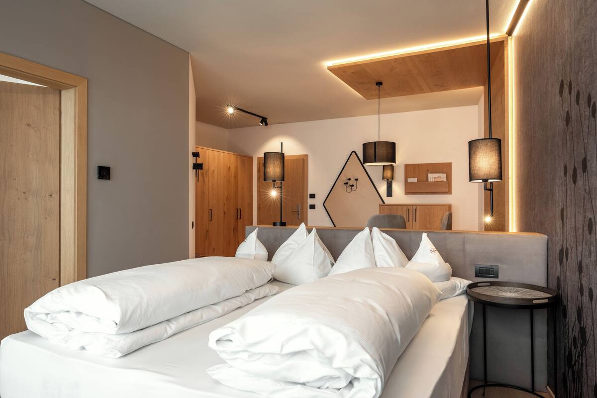 A modern bedroom with a large bed, two bedside tables, and pendant lighting.