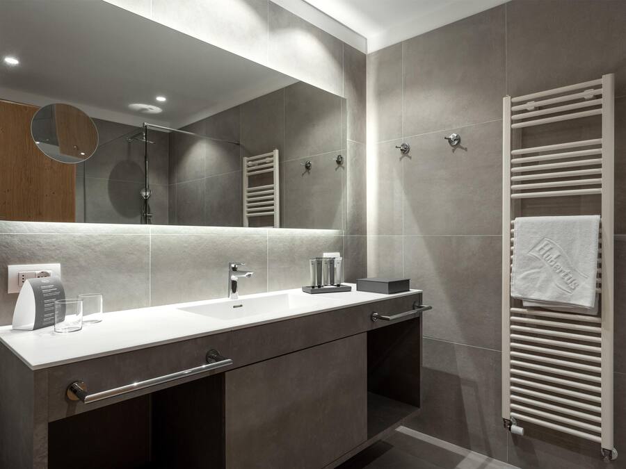 A modern bathroom with a large mirror, a white sink, and a towel rack.