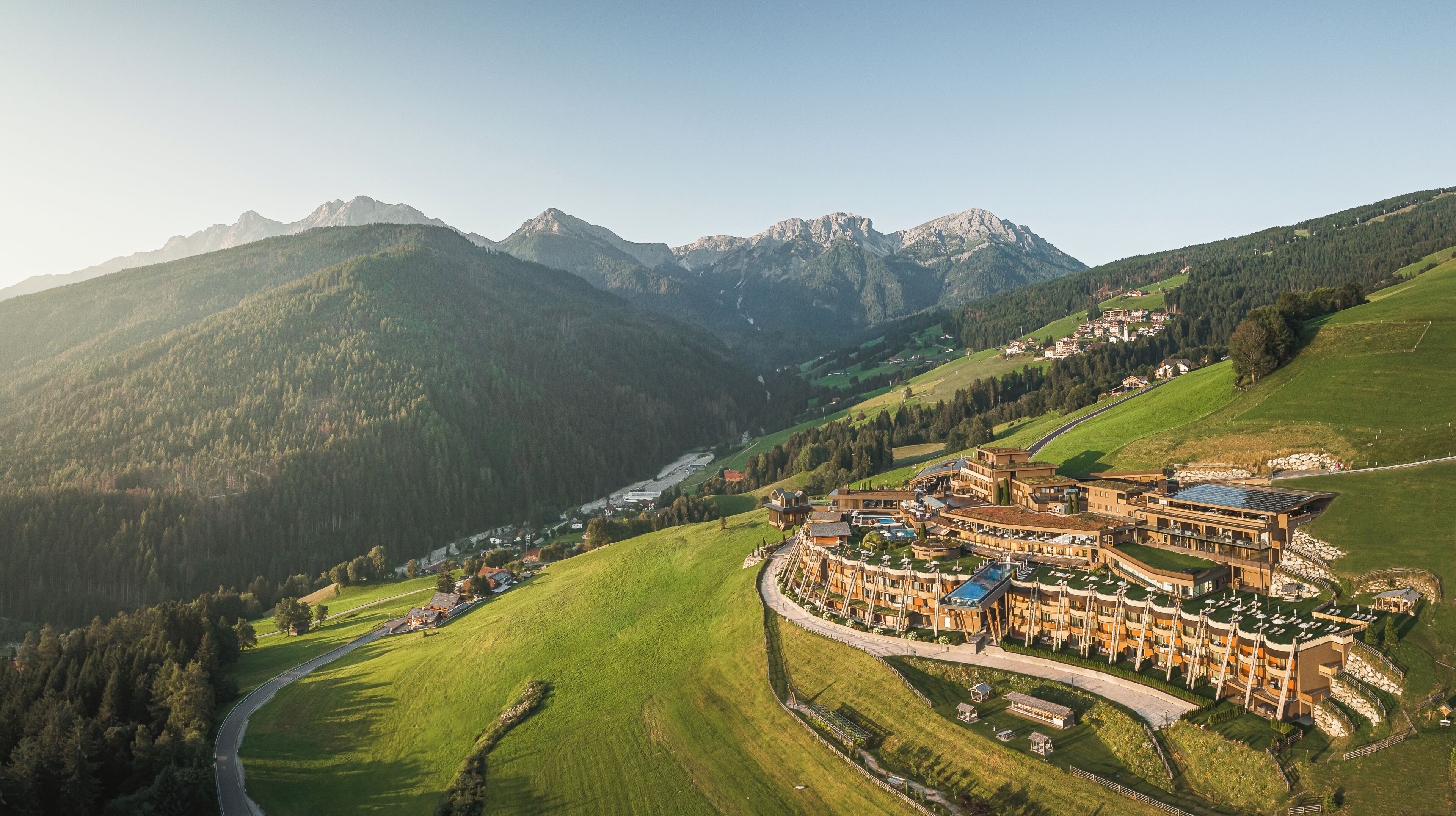 A resort with a winding road, multiple buildings, and a mountainous backdrop.