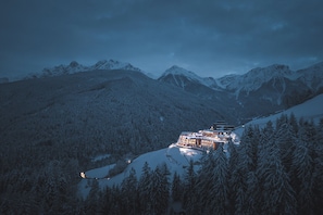 A snow-covered mountain landscape with a lodge featuring multiple buildings and a ski lift. - Hotel Hubertus (Valdaora)