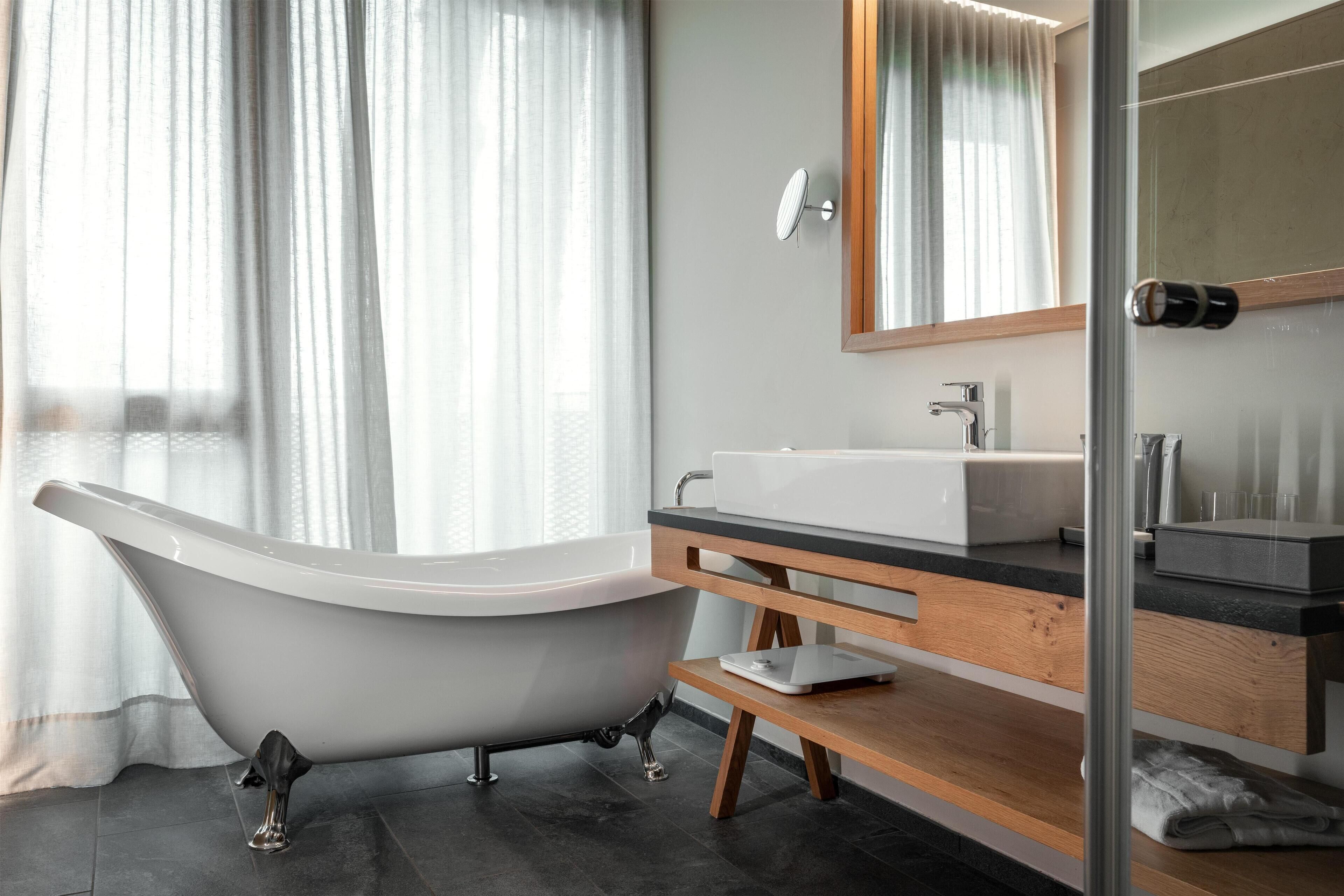Ein modernes Badezimmer mit einer freistehenden Badewanne, einem Holzbadezimmer-Möbel und einem großen Spiegel.