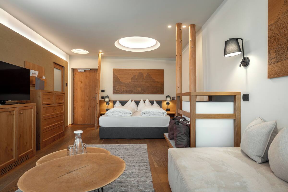 A modern hotel room with a large bed, wooden furniture, a flat-screen TV, and a painting on the wall.