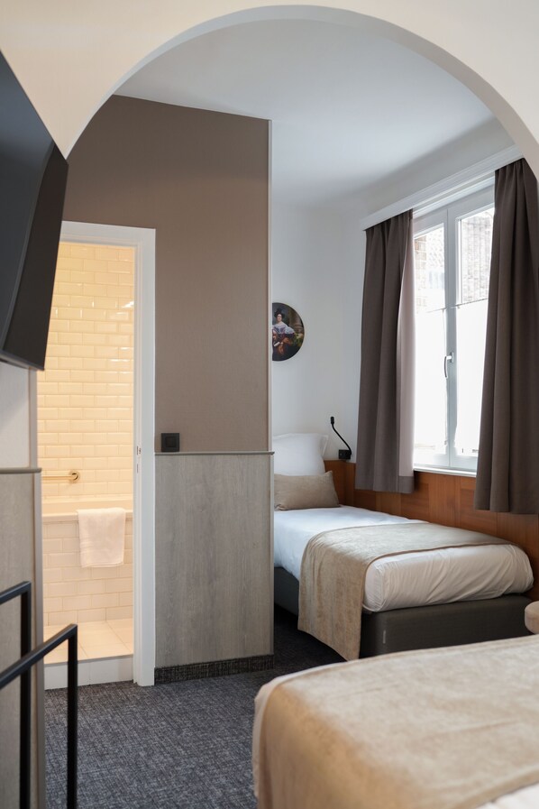 A hotel room with a shower, a bed, a TV, and a window with curtains. - Hotel Jacobs (Bruges)