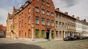 A historic red brick building with a steeply pitched roof, large windows, and a prominent entrance. - Hotel Jacobs (Bruges)