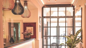 A hotel reception area with a wooden floor, a reception desk, and a potted plant. - Hotel Jacobs (Bruges)
