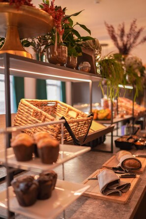 A buffet setup with various food items and decorative plants.