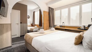 A hotel room with a large bed, a desk with a lamp, a TV mounted on the wall, and a window with curtains. - Hotel Jacobs (Bruges)