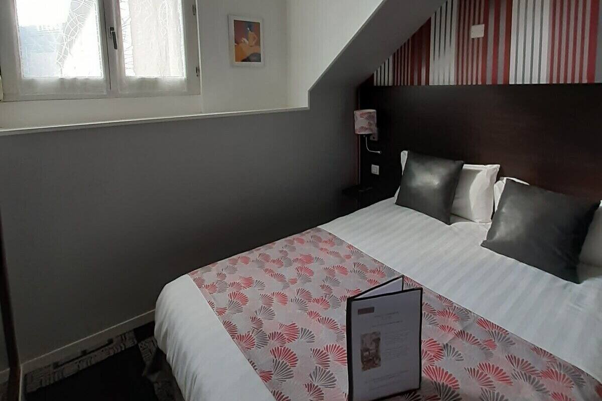 A bedroom with a bed, a window, a bedside table, and a nightstand.