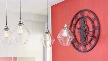 A room with a red wall, a large clock, and three pendant lights.