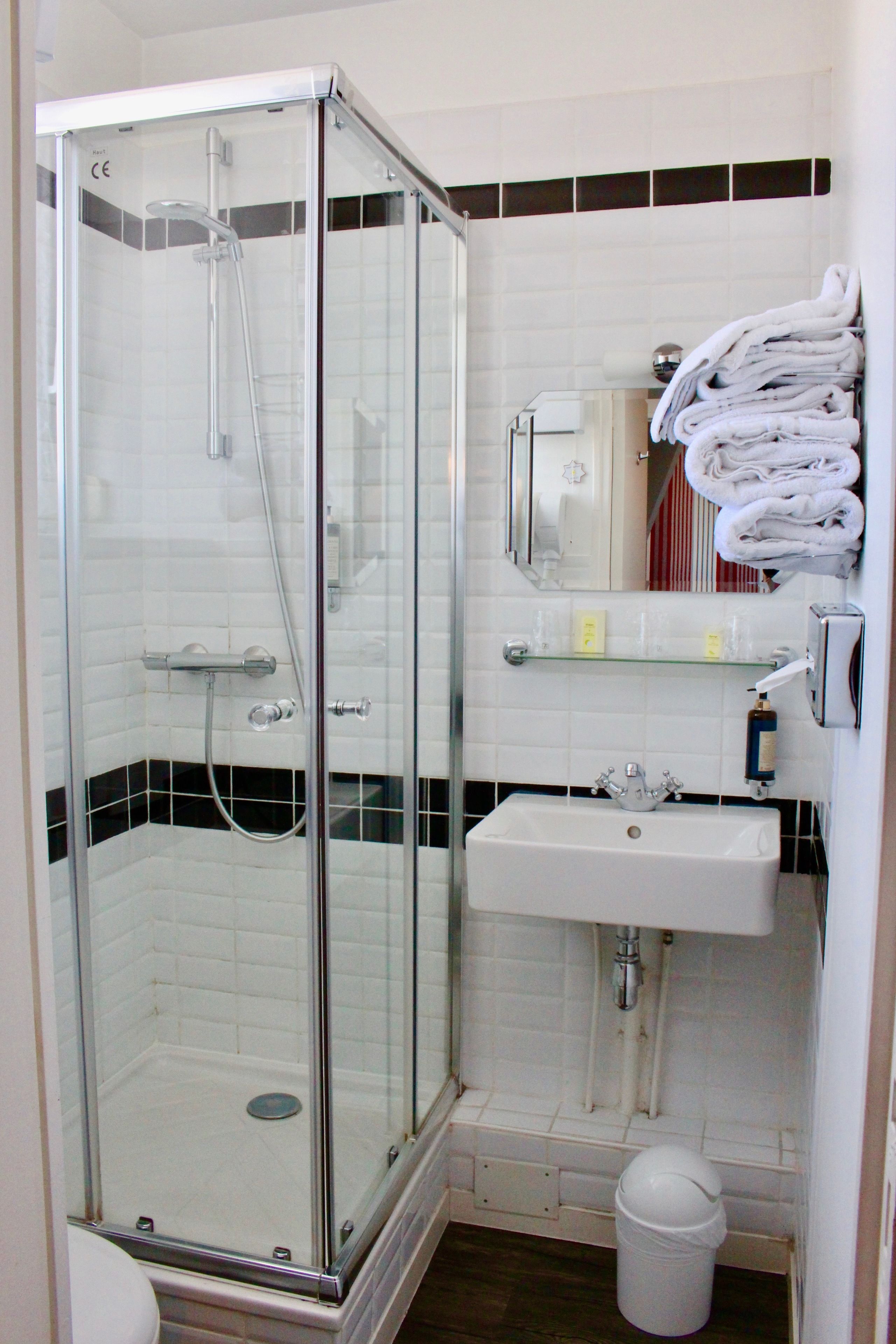 A glass-enclosed shower with a white sink and a towel rack.