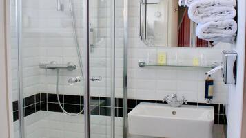 A glass-enclosed shower with a white sink and a towel rack.