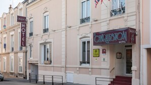 Ein Hotelgebäude mit einer Schrifttafel mit dem Schriftzug "Charleston Hotel", mehreren Flaggen und einem sichtbaren Eingang mit Stufen.