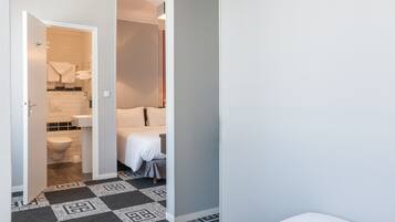 Ett hotellrum med badrum, en säng och ett mönstrat golv.