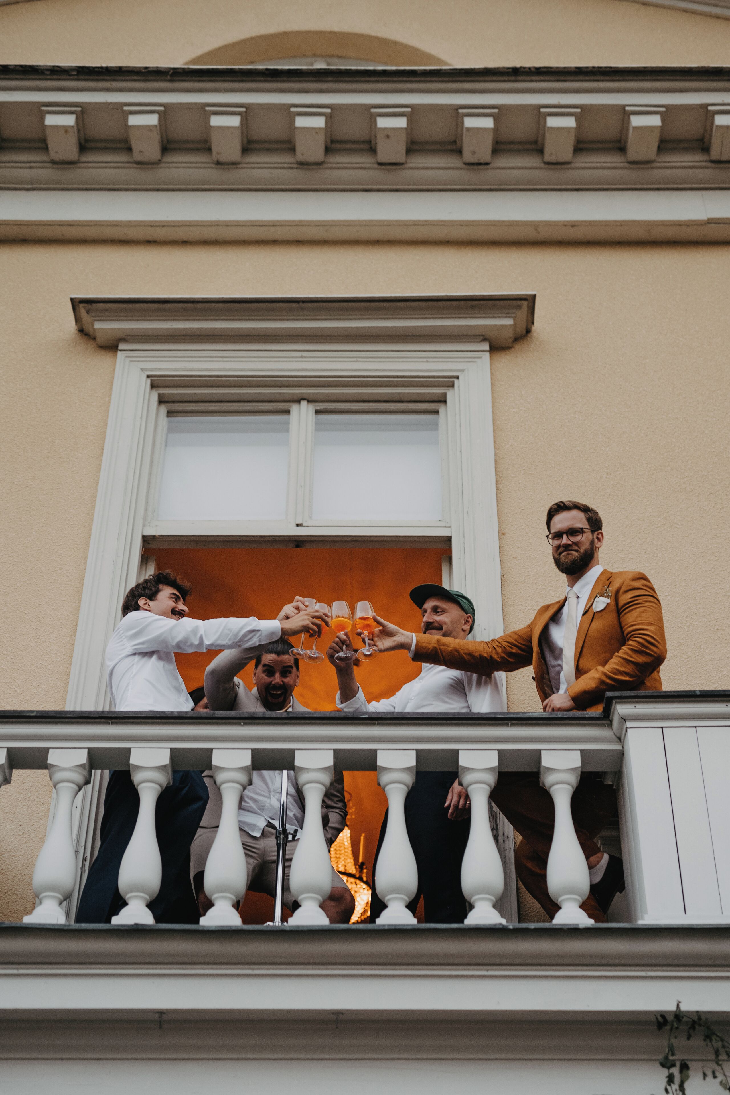 En balkong med vita balustrader och en byggnadsfasad med ett fönster och dekorativa lister.