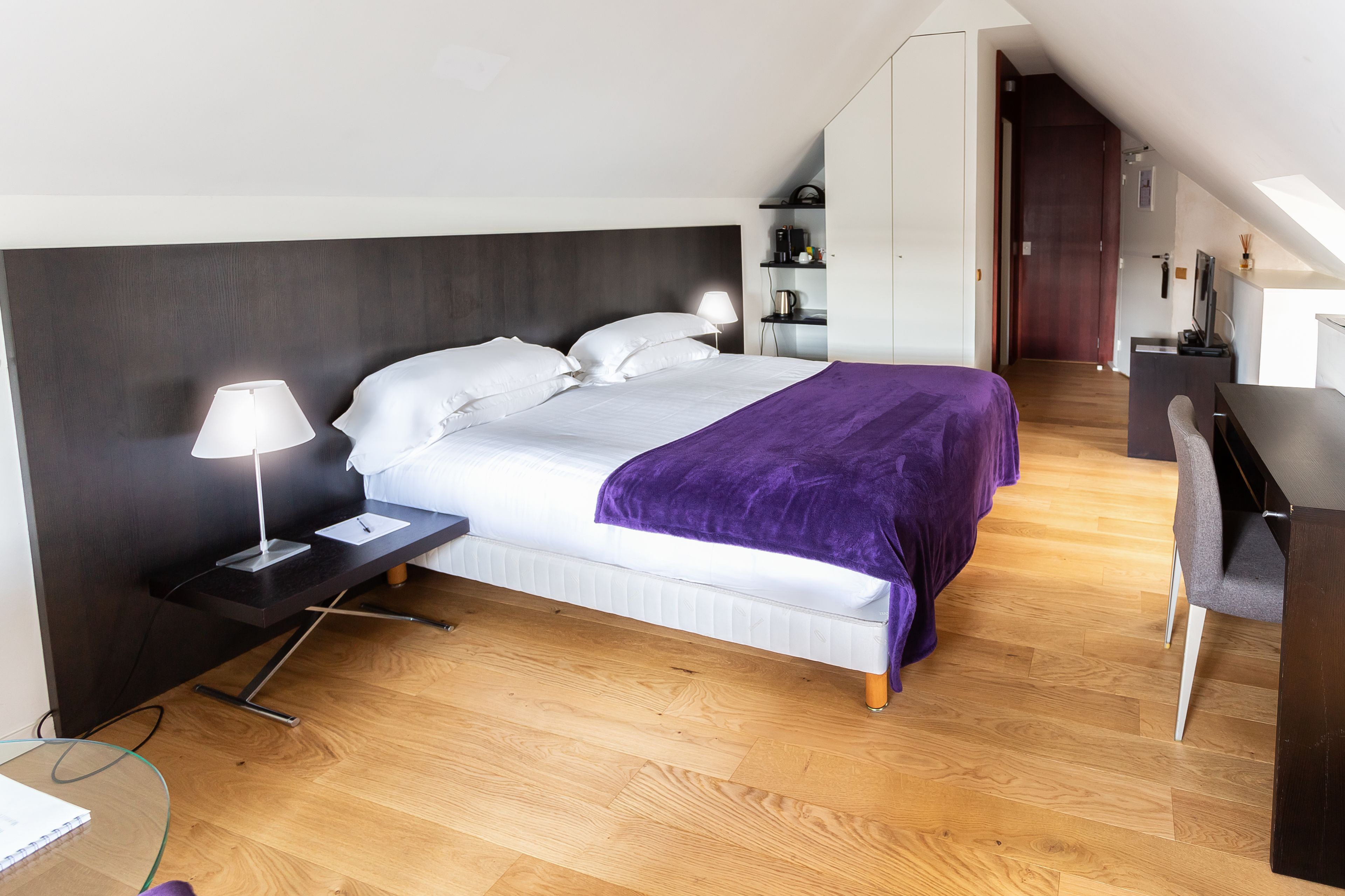 A modern bedroom with a bed, bedside tables, a desk, and a wardrobe.