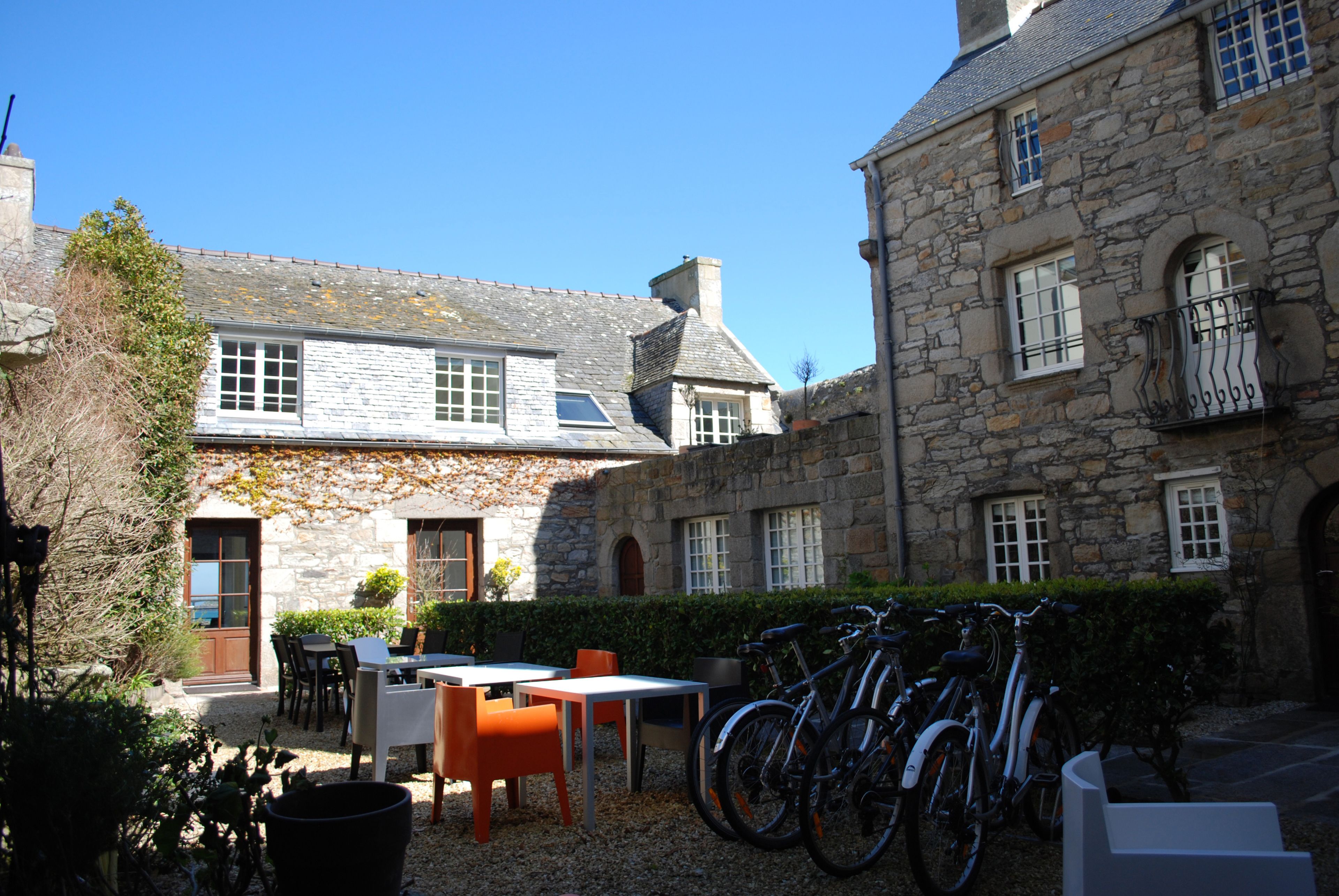 A stone building with a courtyard, outdoor seating, and bicycles.
