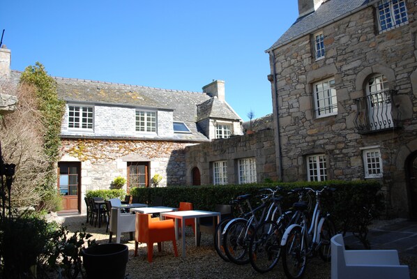 Un edificio de piedra con patio, mesas al aire libre y bicicletas.