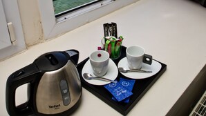 Vista desde una ventana con una mesa lista para el desayuno, que incluye un hervidor, tazas y condimentos.