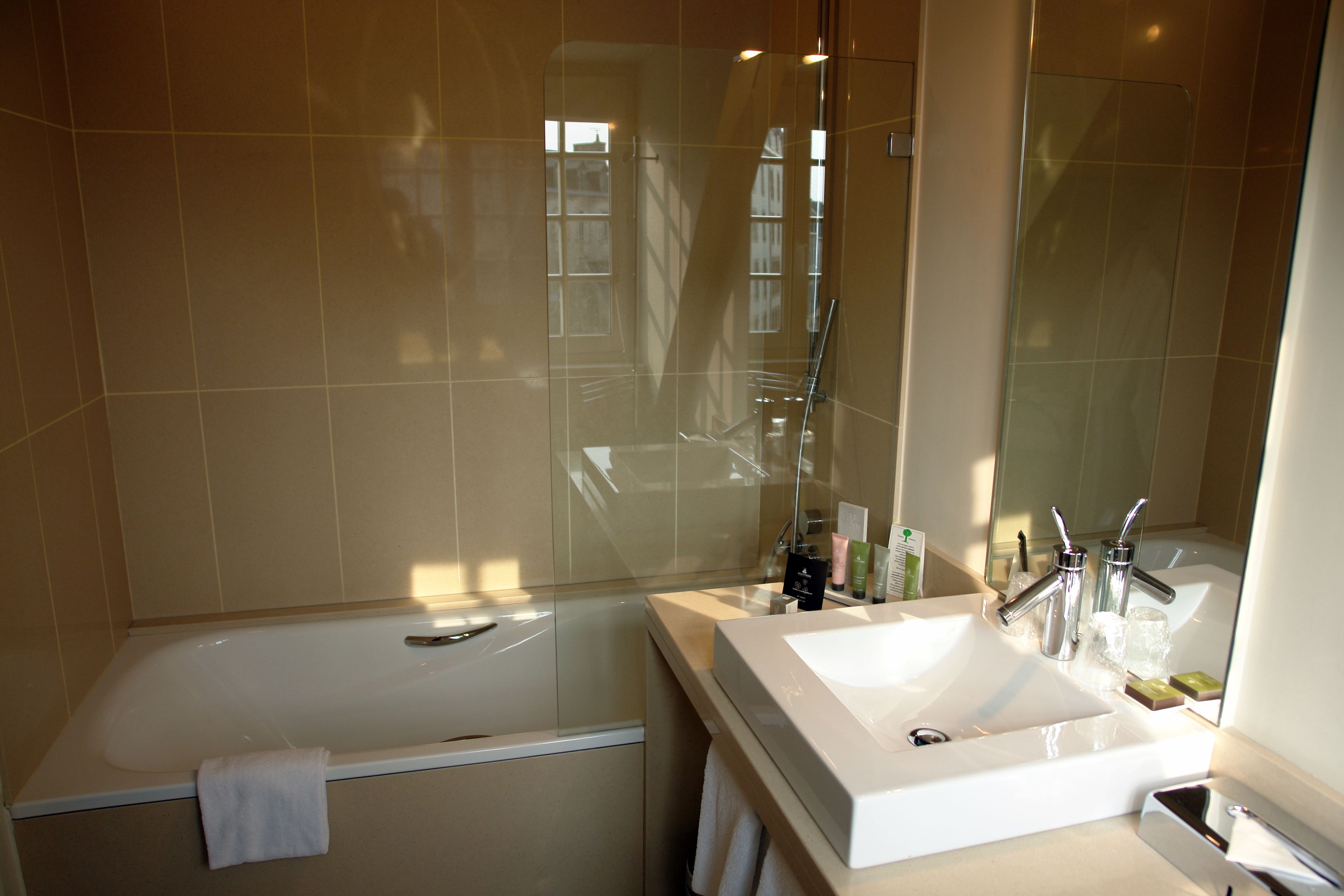 A modern bathroom with a bathtub, a sink, and a large mirror.