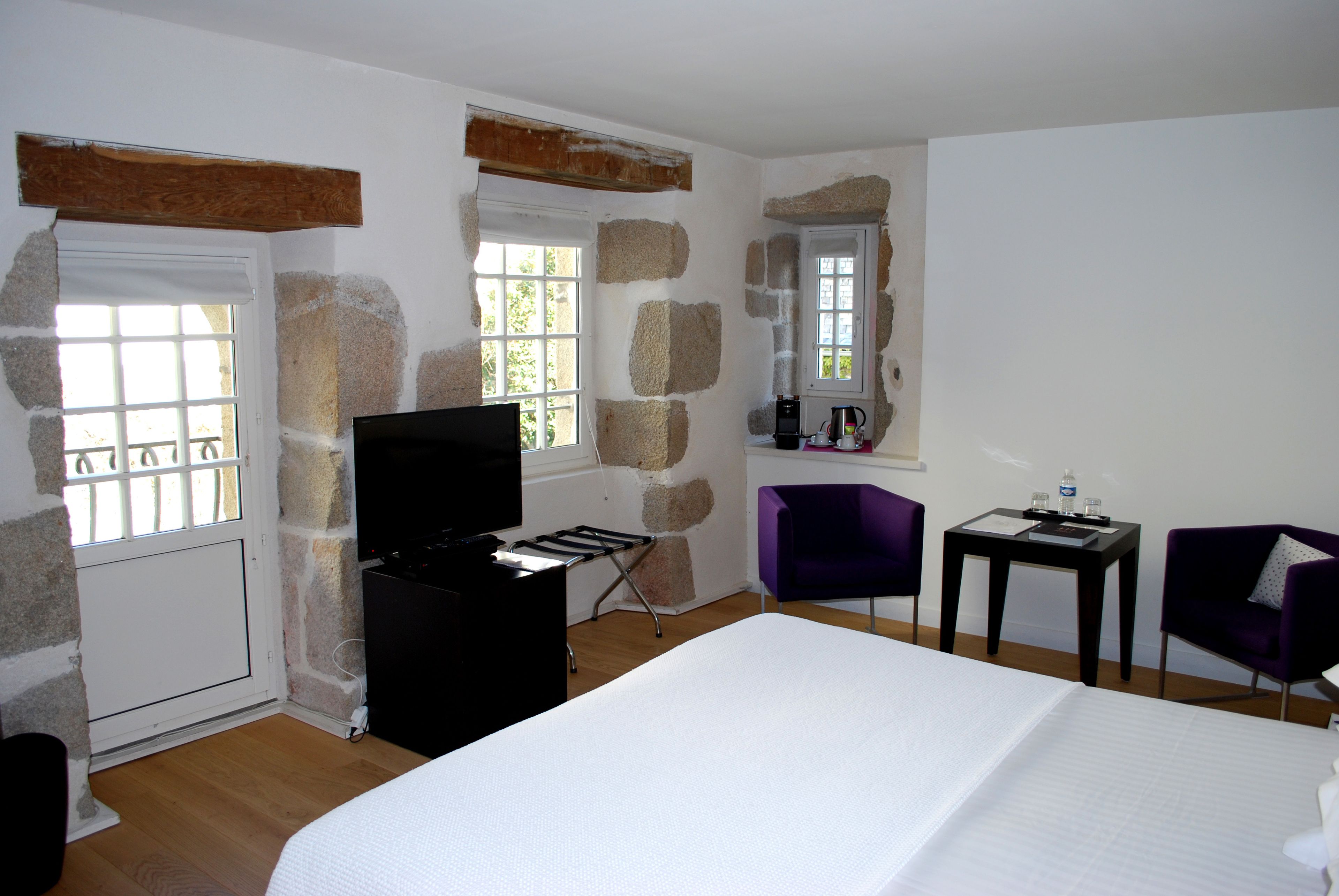Una habitación de hotel con cama, escritorio, silla y televisor.