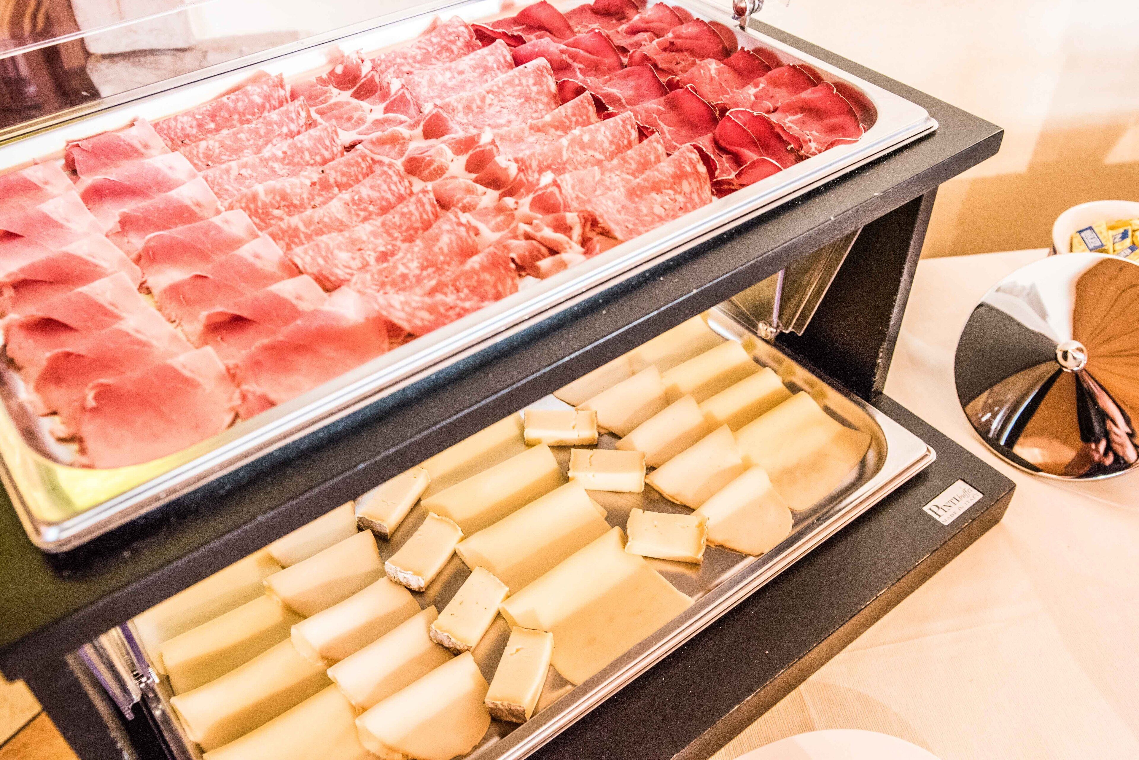 Un bufé con diversas opciones de comida, incluyendo carnes y quesos.