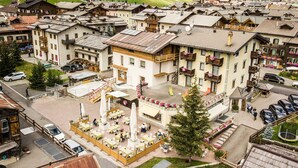 A traditional alpine village with chalet-style buildings, outdoor seating areas, and a central square with a fountain. - Hotel Angelica (Livigno)