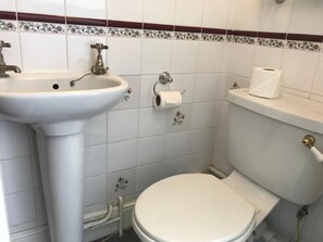 A small bathroom with a white sink, toilet, and a toilet paper holder. - Timrick Lodge Hotel (Weymouth)