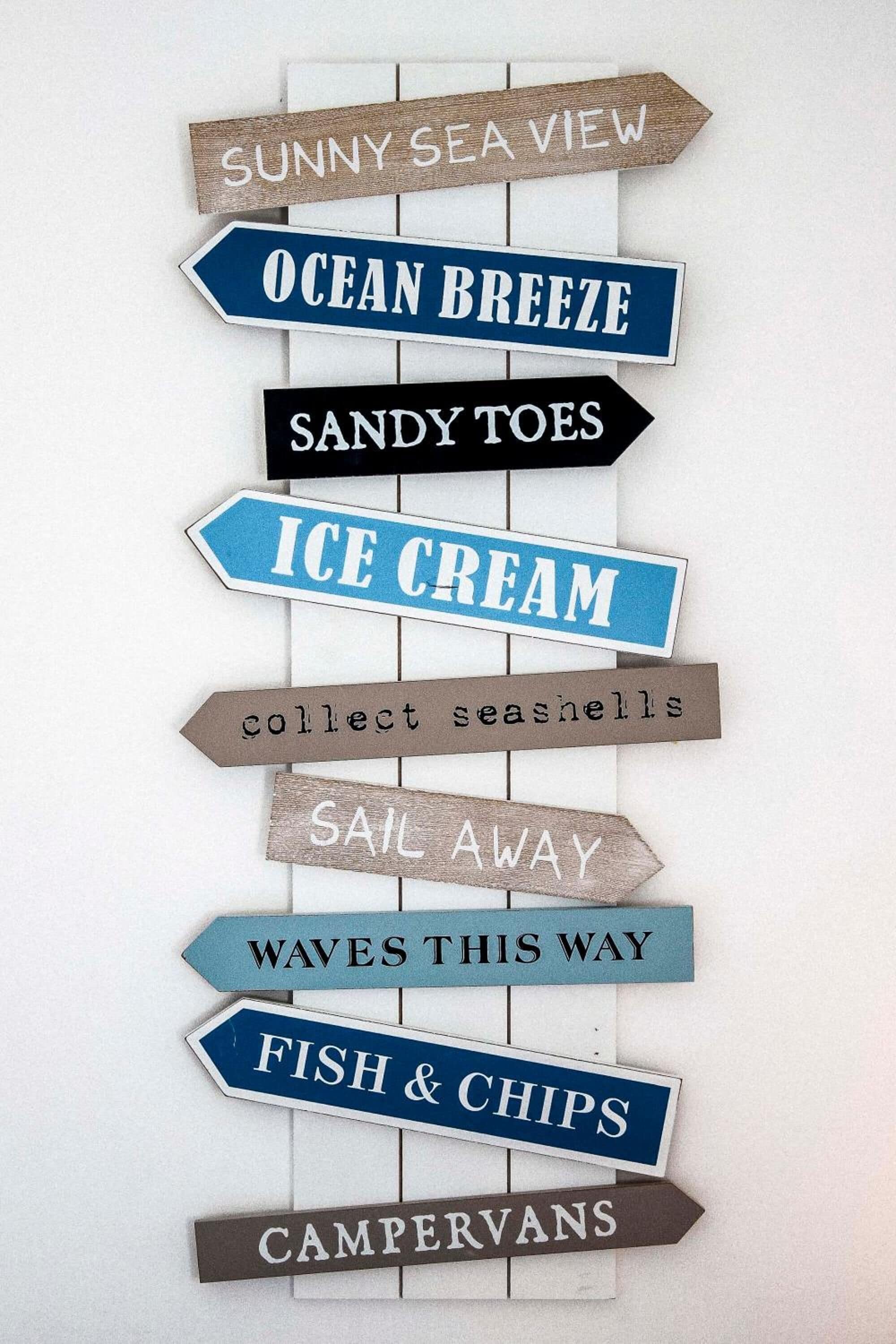 Disposición vertical de letreros con temática náutica que incluyen textos como 'VISTA AL MAR SOLEADA', 'BRISA MARINA' y 'PIES DE arena'.