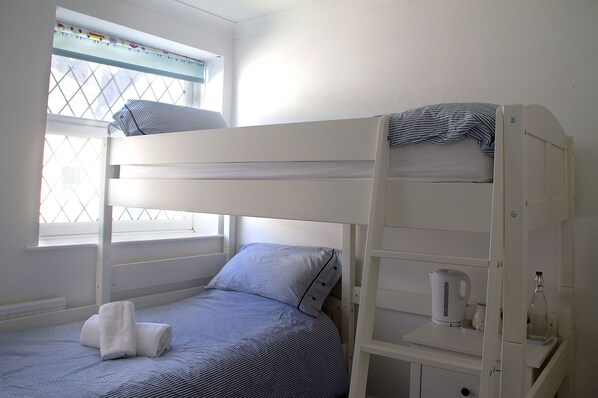 A bunk bed with a window, a small bedside table with a kettle, and a bottle. - Timrick Lodge Hotel (Weymouth)