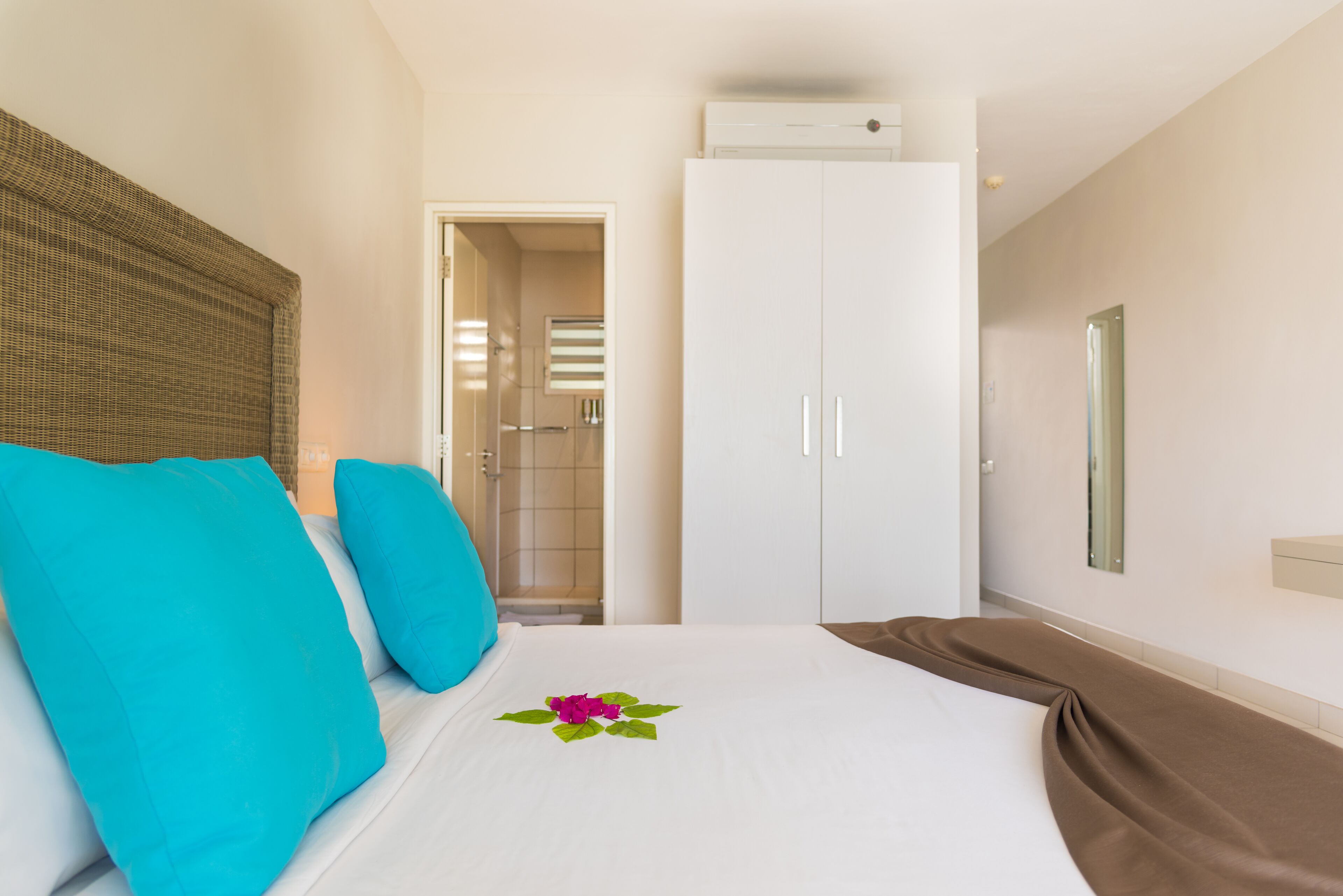 Habitación de hotel con cama, armario y baño visible a través de una puerta abierta.