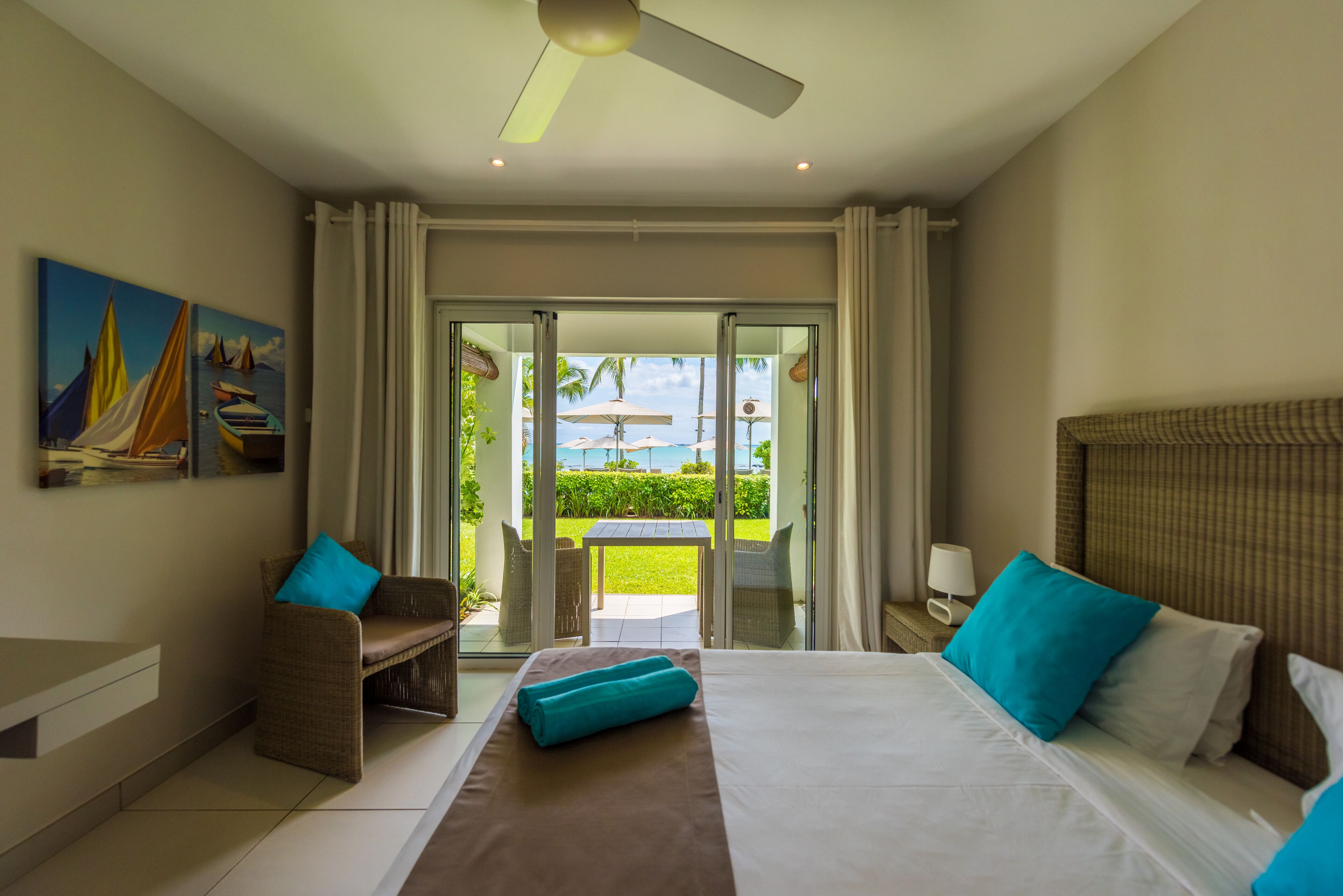 A hotel room with a bed, a seating area with a view, and a painting on the wall.