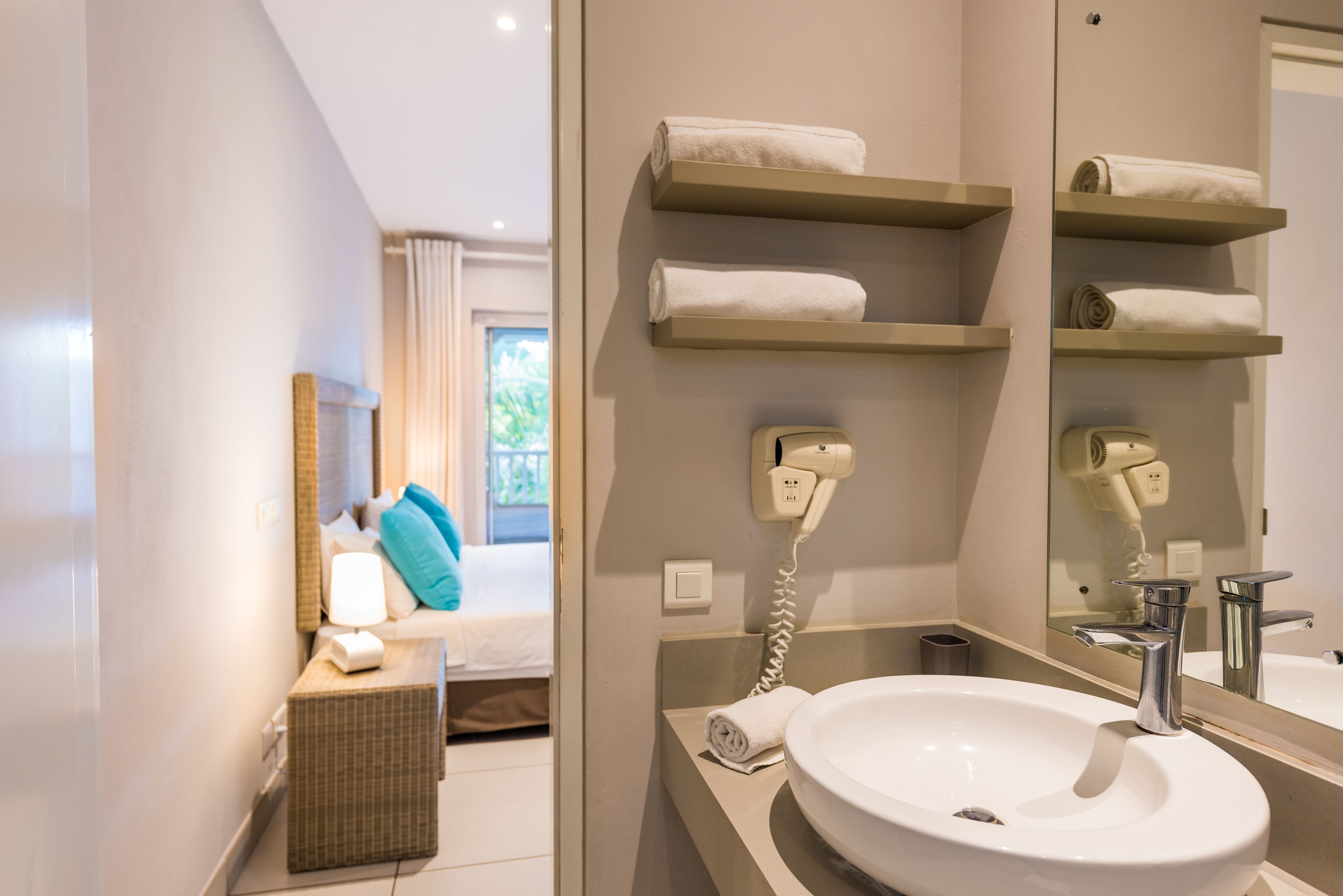 A modern bathroom with a large mirror, a white sink, and two towel racks.